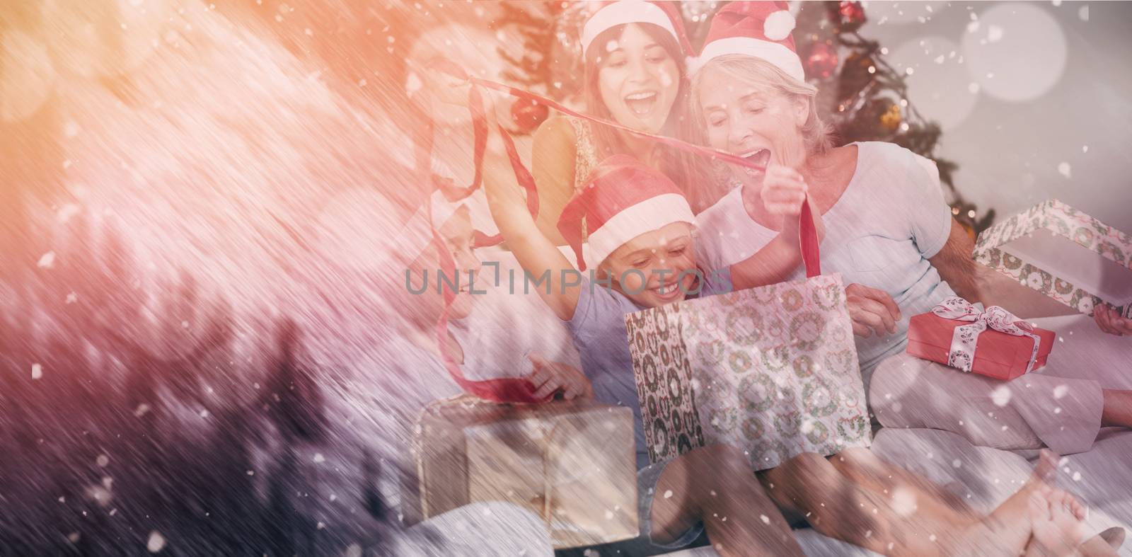 Happy family at christmas opening gifts together against snowy pine trees on alp mountain slope