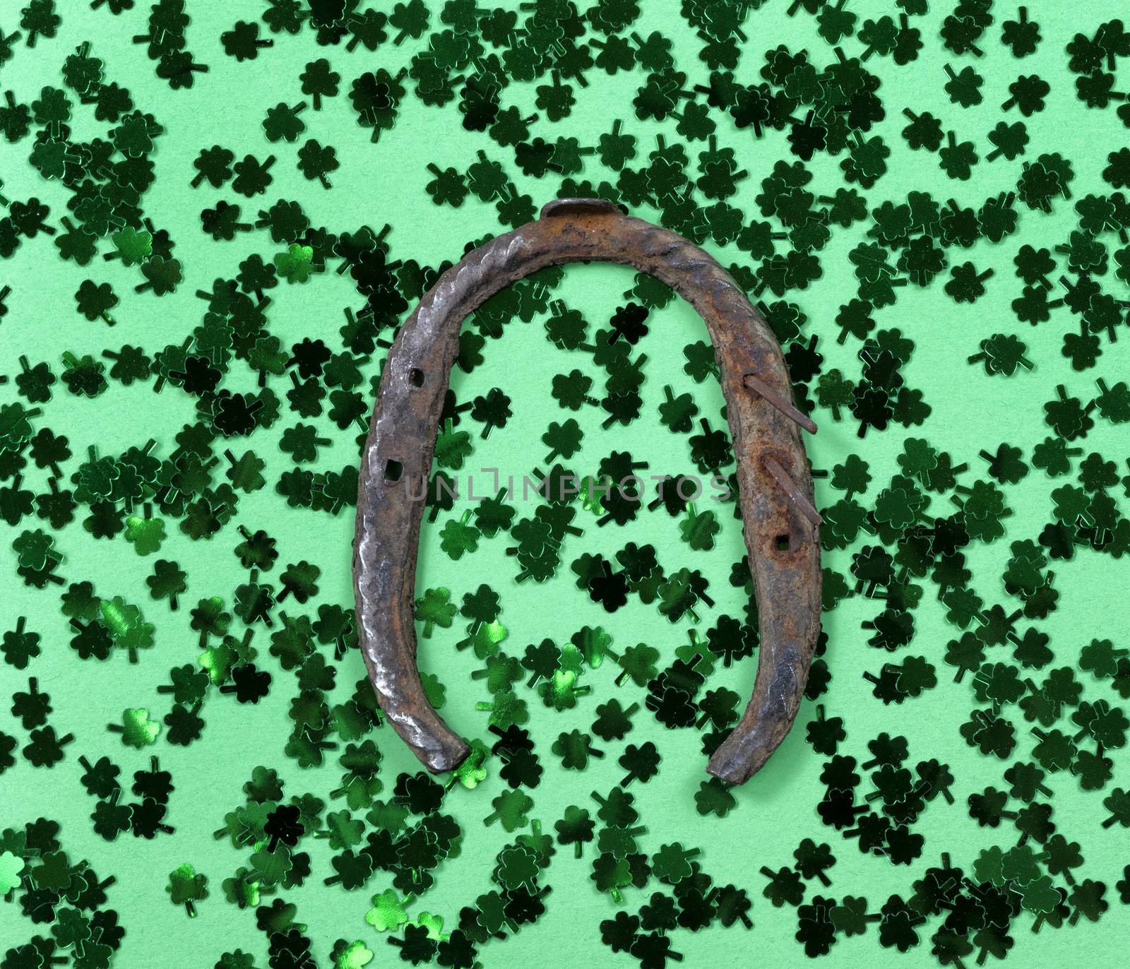 Saint Patricks Day with shamrocks and rusty horseshoe on green background in filled frame format 