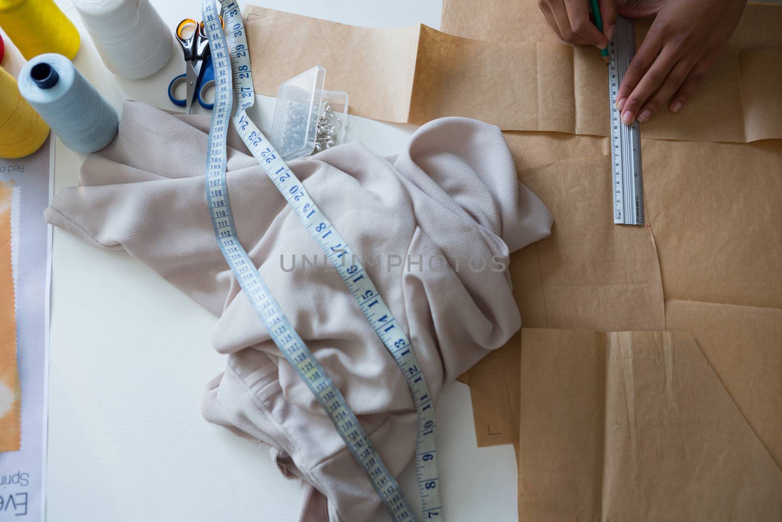 Overhead of fashion designer marking on brown paper