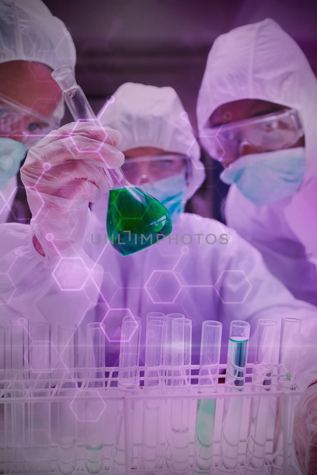 Digital data  against  chemists in protective suits looking at green liquid in beaker Chemists in protective suits looking at green liquid in beaker in the lab