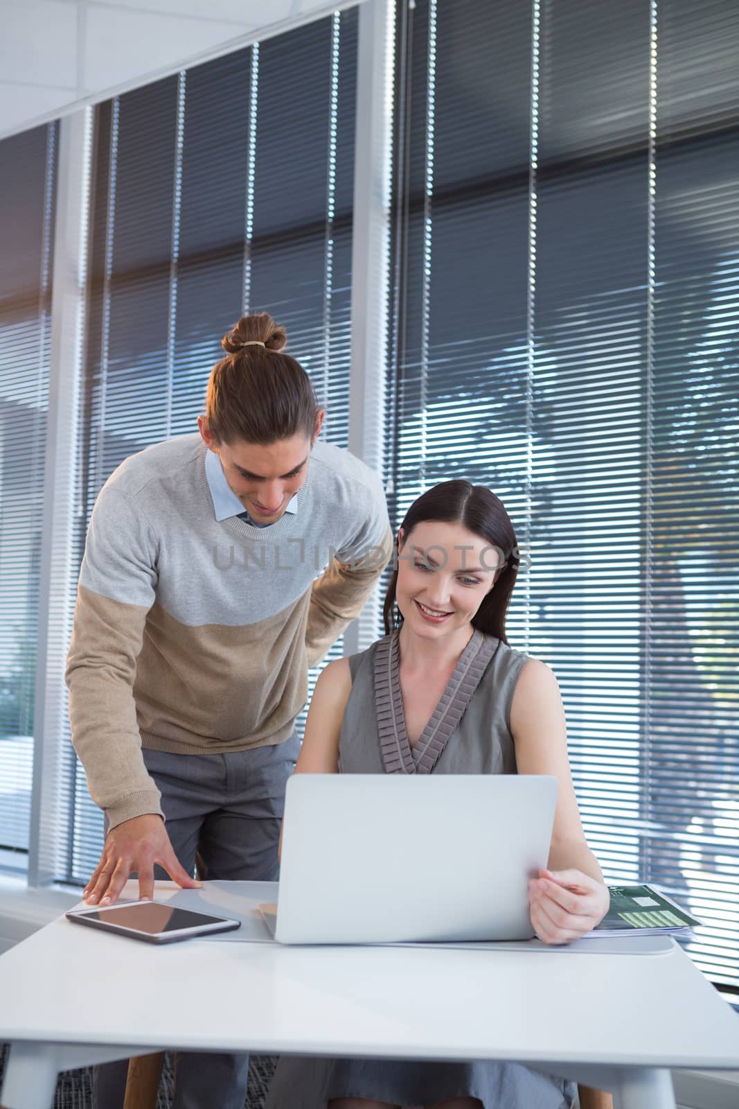 Business executives discussing over laptop at desk in office