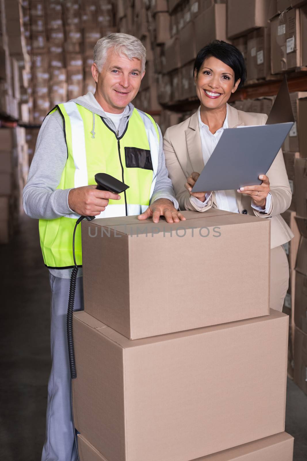 Warehouse worker scanning box with manager in a large warehouse