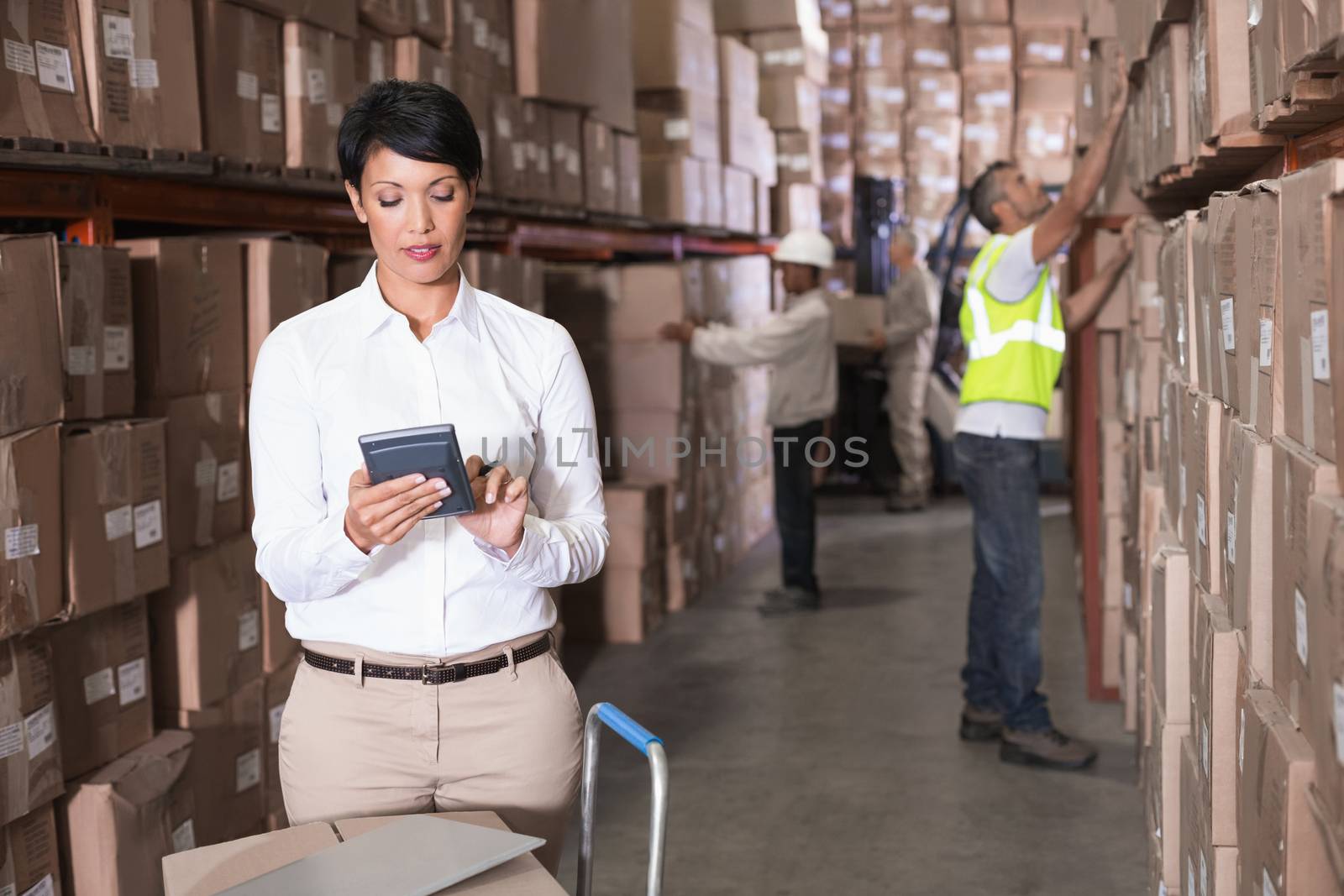 Pretty warehouse manager using calculator in a large warehouse