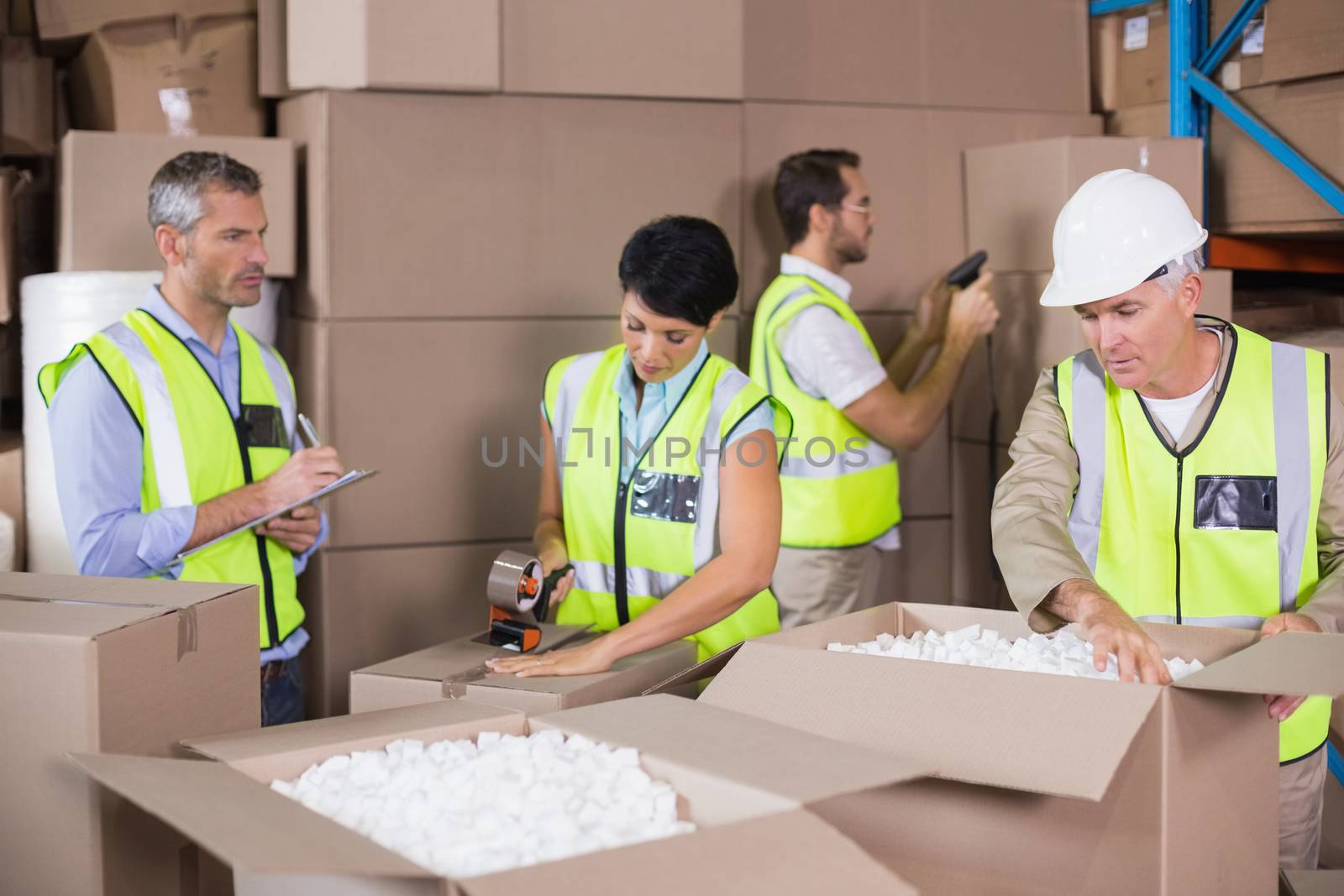 Warehouse workers in yellow vests preparing a shipment in a large warehouse