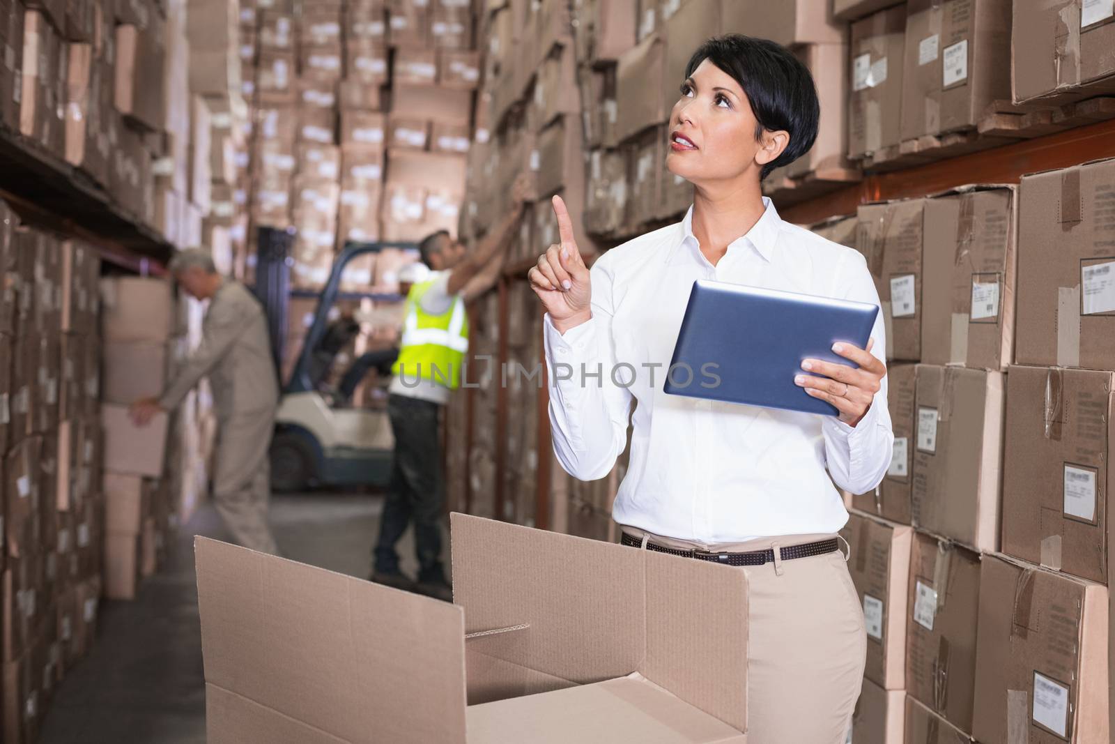 Pretty warehouse manager using tablet pc in a large warehouse