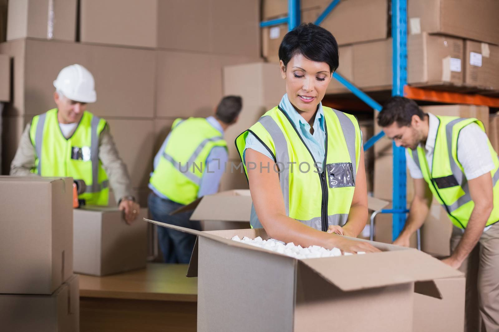 Warehouse workers in yellow vests preparing a shipment in a large warehouse