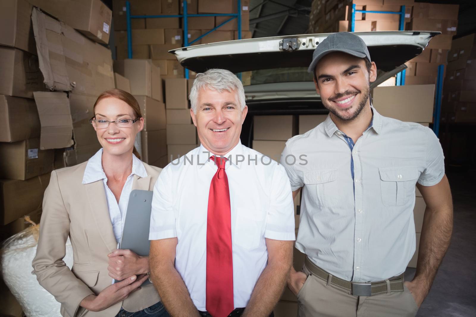 Warehouse managers and delivery driver smiling at camera by Wavebreakmedia