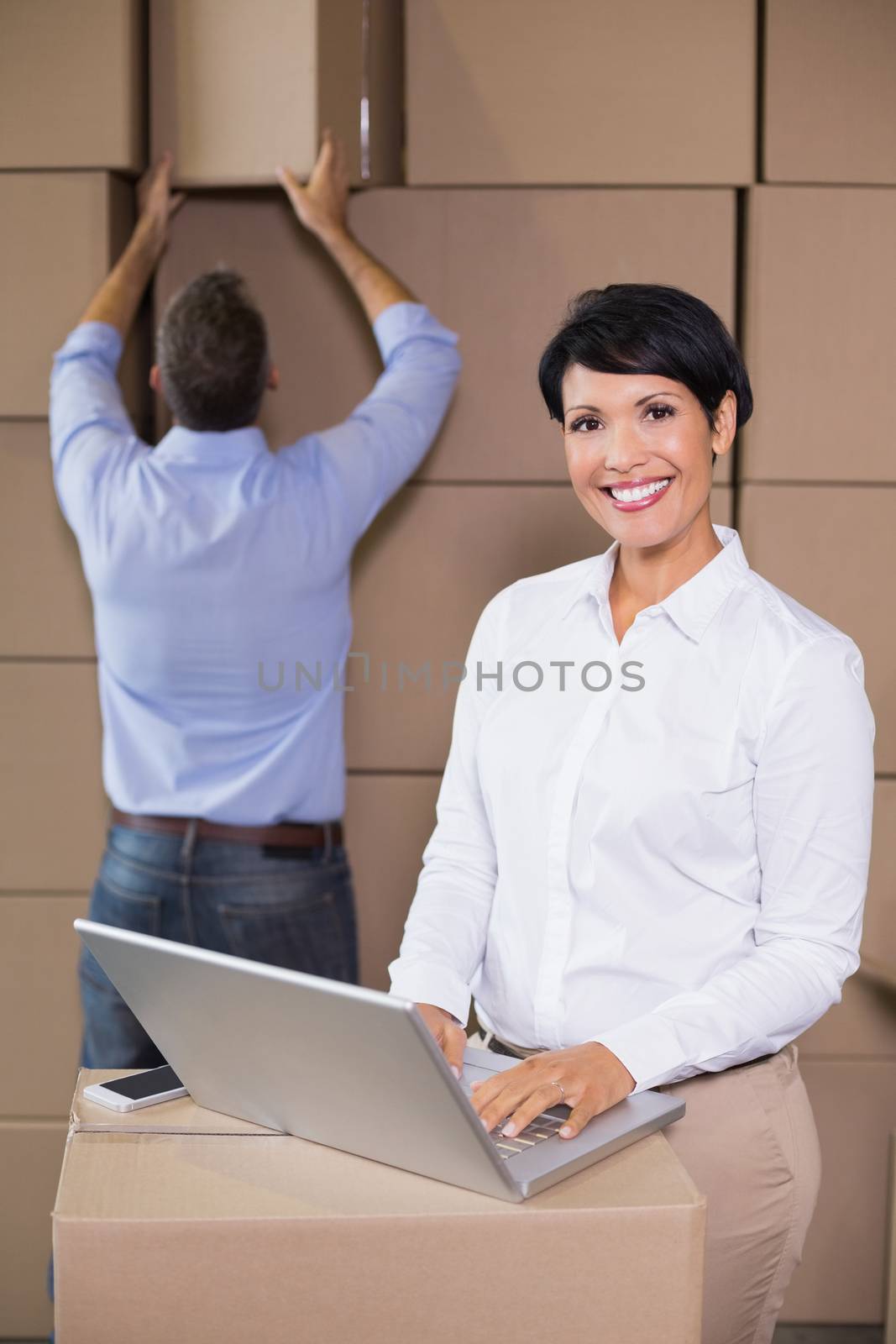 Pretty warehouse manager using laptop in a large warehouse