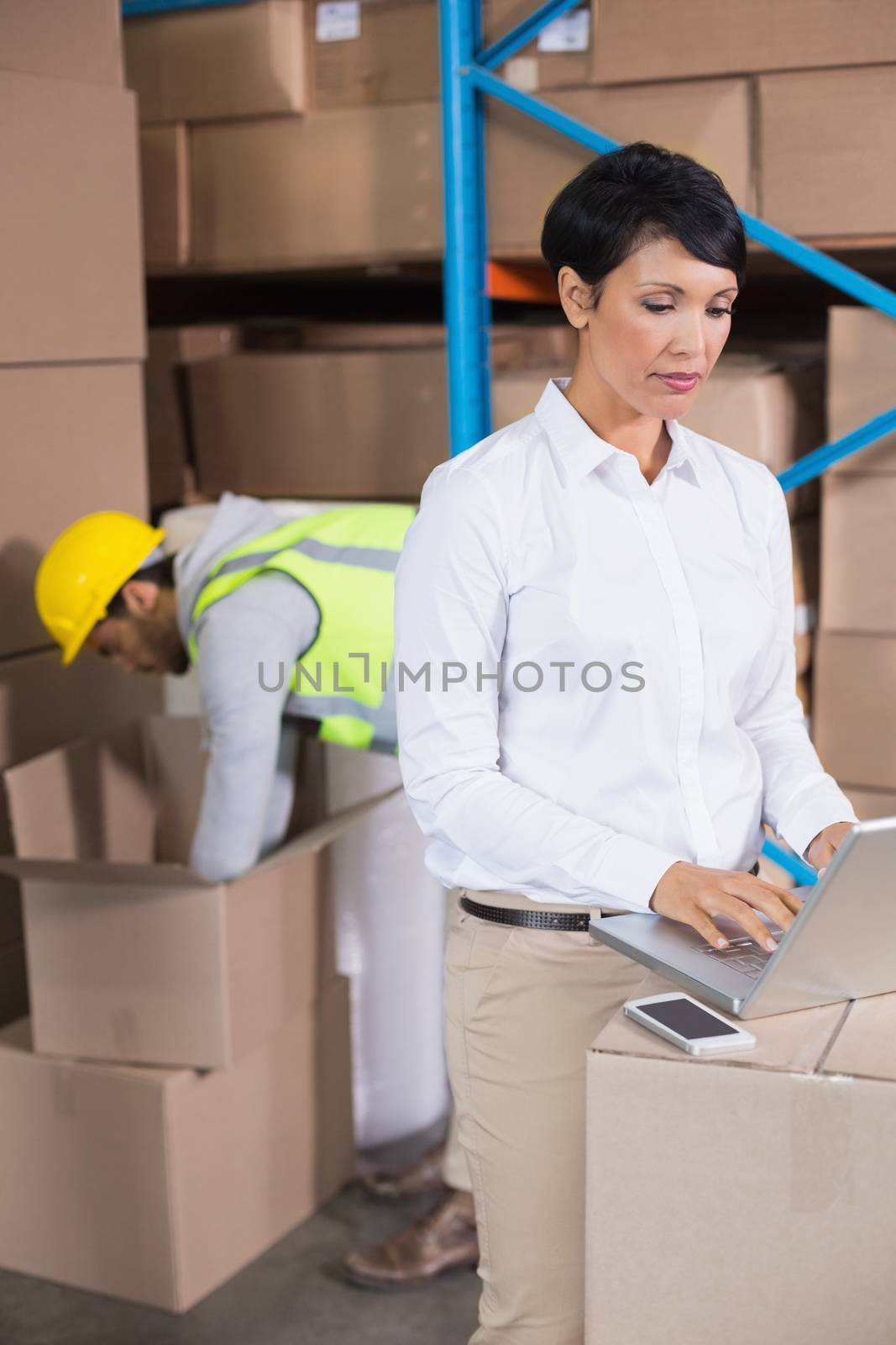 Pretty warehouse manager using laptop by Wavebreakmedia