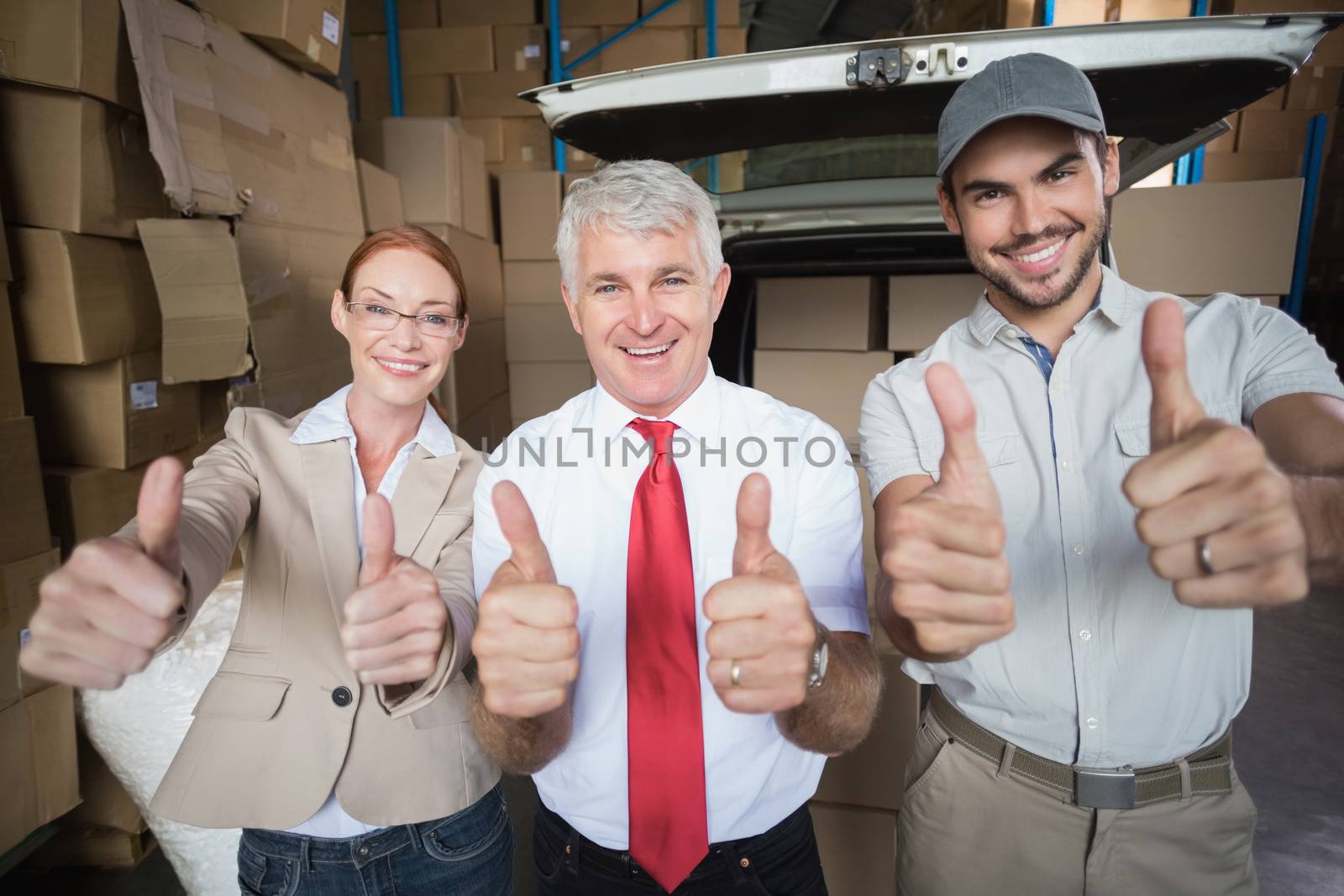 Warehouse managers and delivery driver smiling at camera by Wavebreakmedia