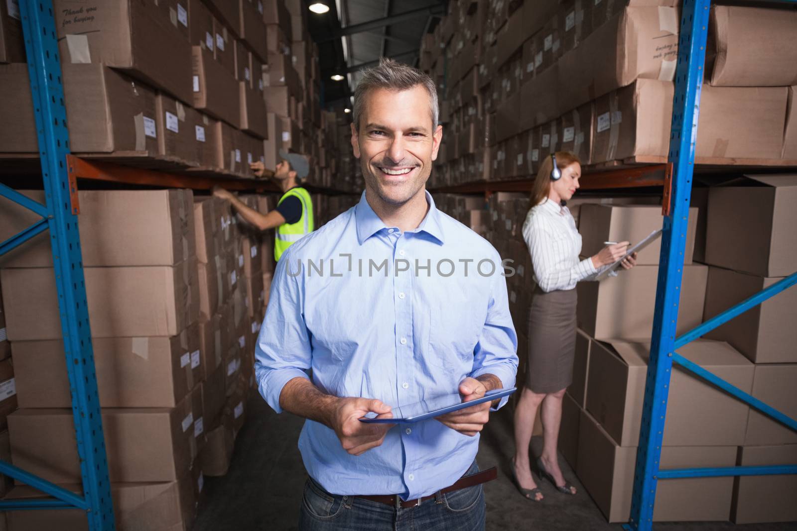 Warehouse manager smiling at camera in a large warehouse