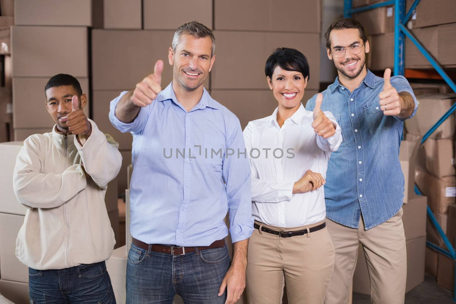 Warehouse workers smiling at camera in a large warehouse