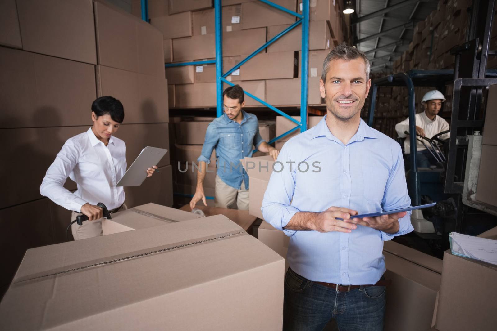 Warehouse manager using his tablet pc in a large warehouse