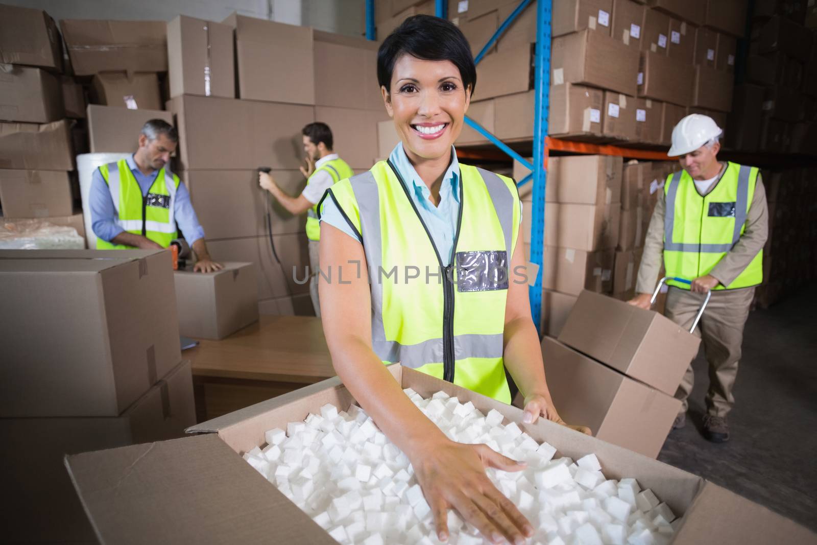 Warehouse workers in yellow vests preparing a shipment in a large warehouse