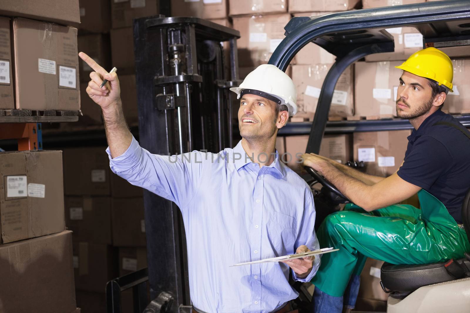 Warehouse manager talking with forklift driver by Wavebreakmedia