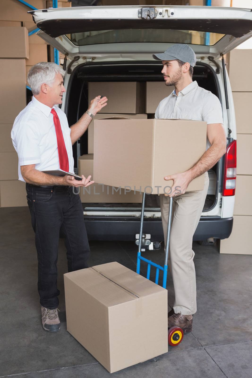 Warehouse manager and delivery driver talking beside van by Wavebreakmedia