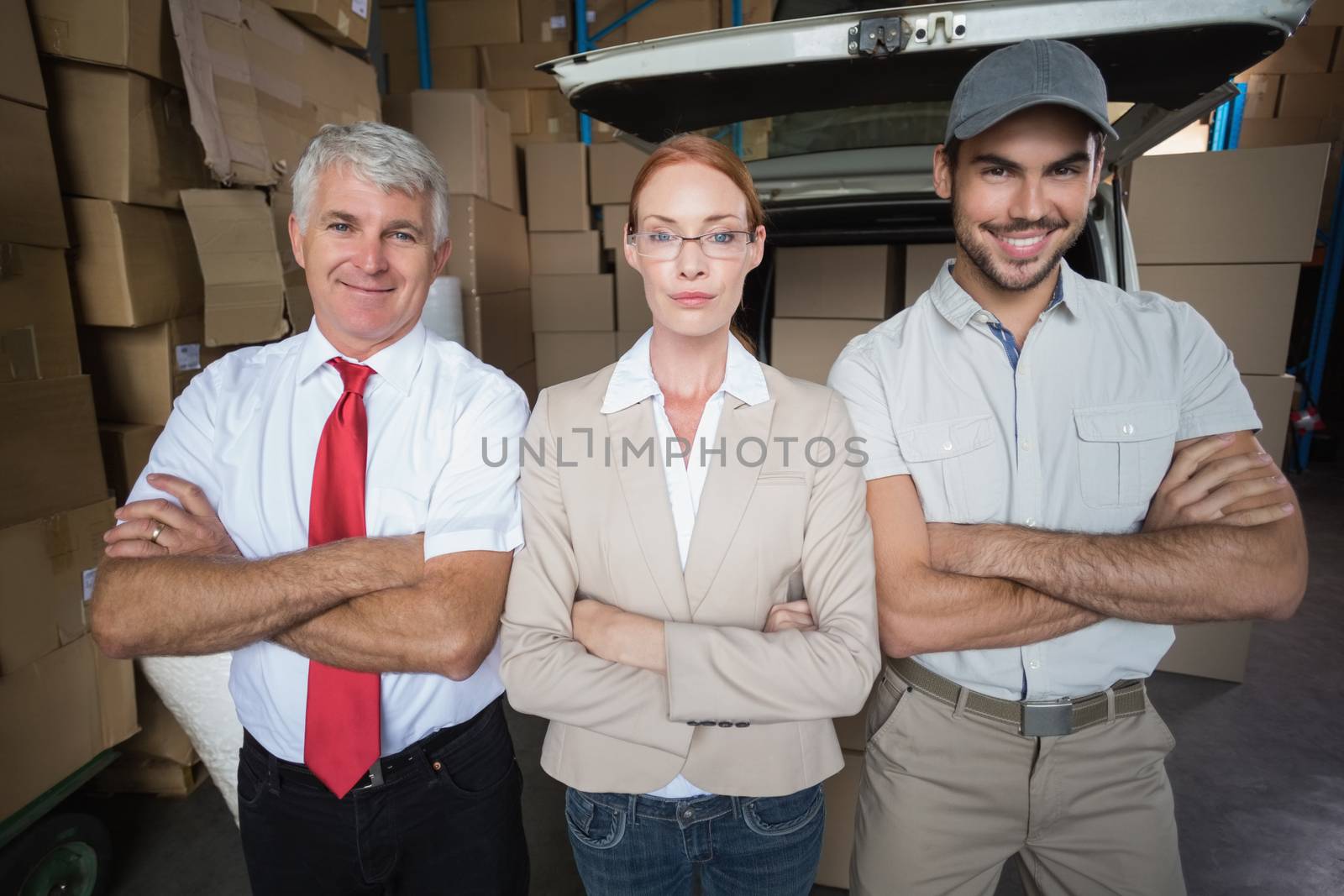 Warehouse managers and delivery driver smiling at camera in a large warehouse