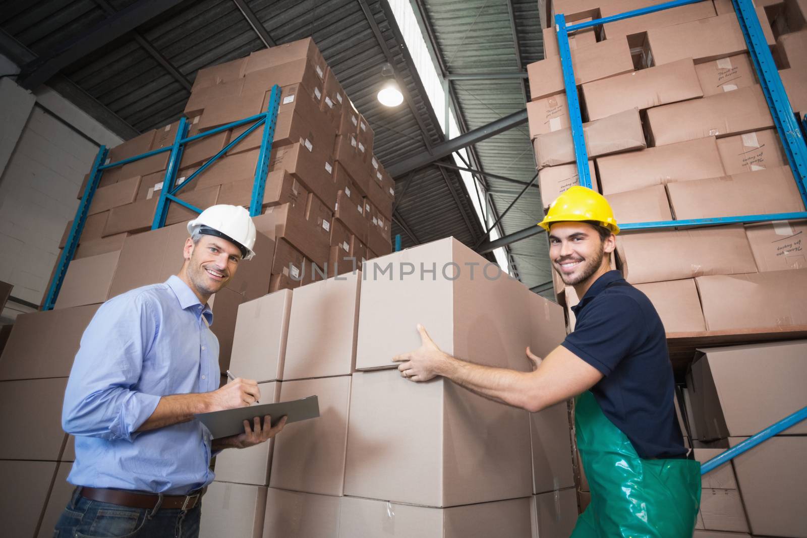 Warehouse worker loading up a pallet with manager in a large warehouse