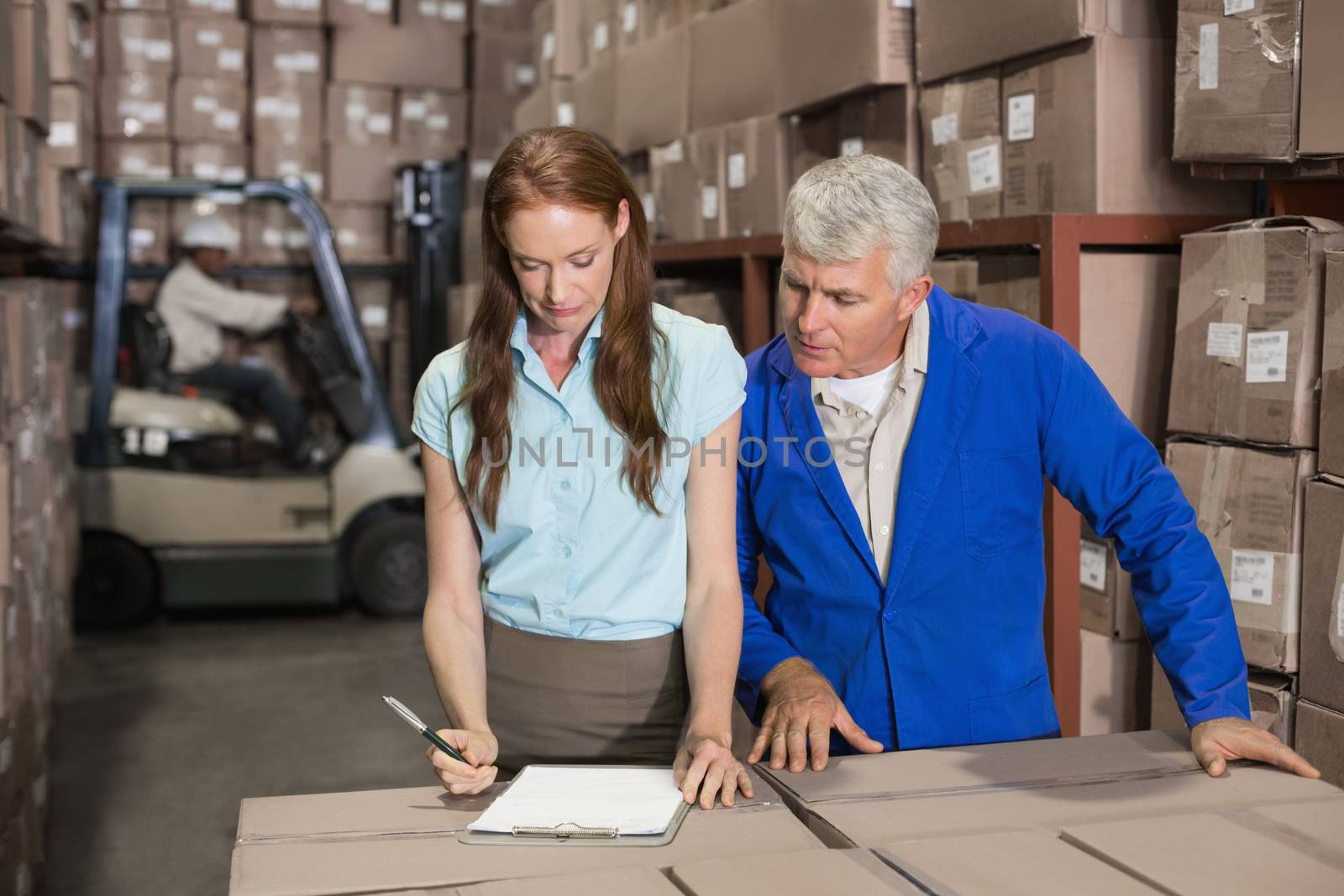 Warehouse manager and foreman working together in a large warehouse