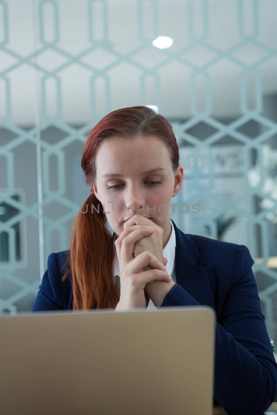 Thoughtful businesswoman using laptop at desk in office