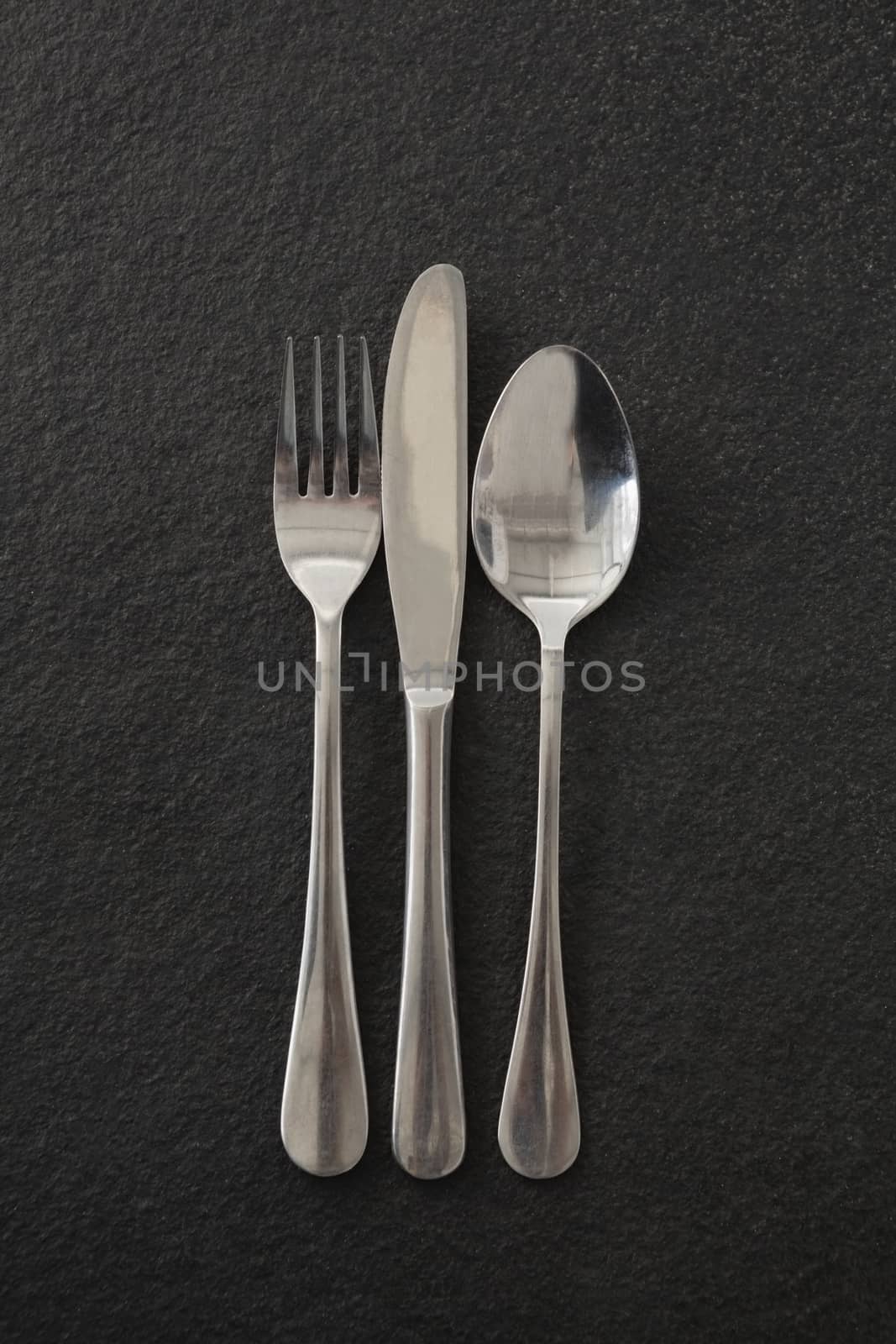 Close-up of fork, spoon and knife on black background