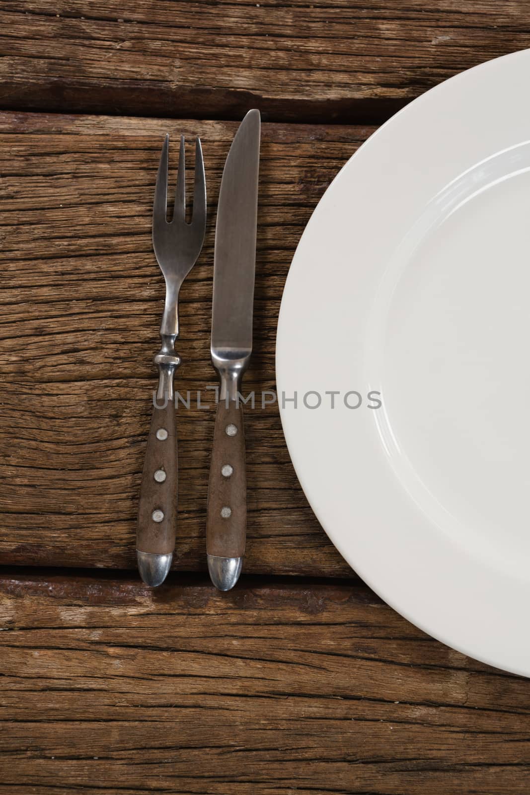 Overhead view of plate with fork and butter knife on wooden table