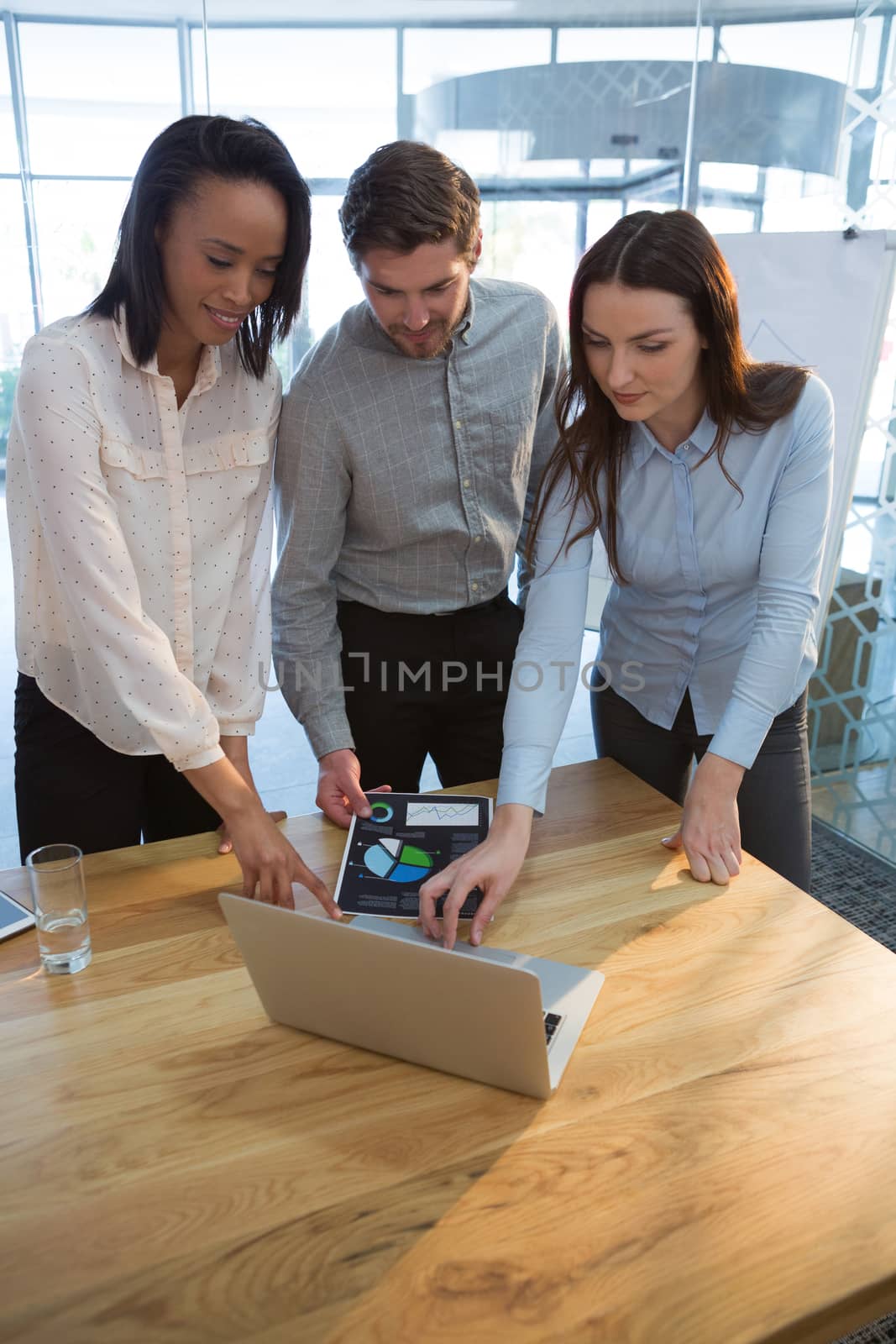 Business colleagues using laptop in conference room at office