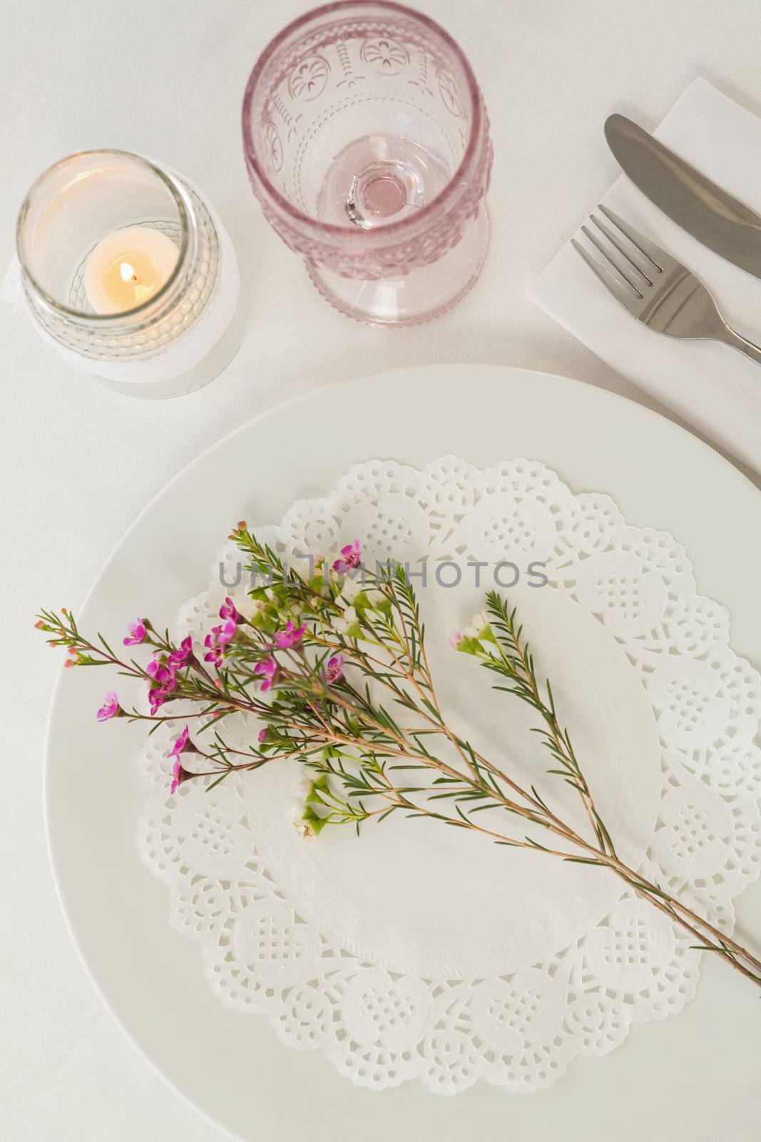 Overhead of flower kept over an embroidery napkin plate with cutlery