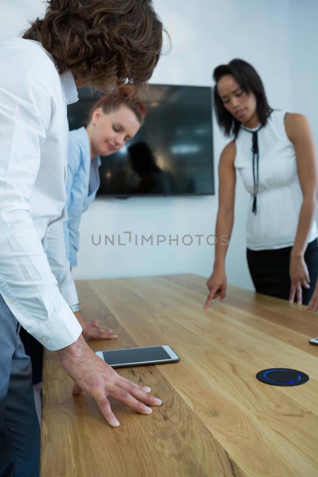 Group of executive looking at phone on table by Wavebreakmedia