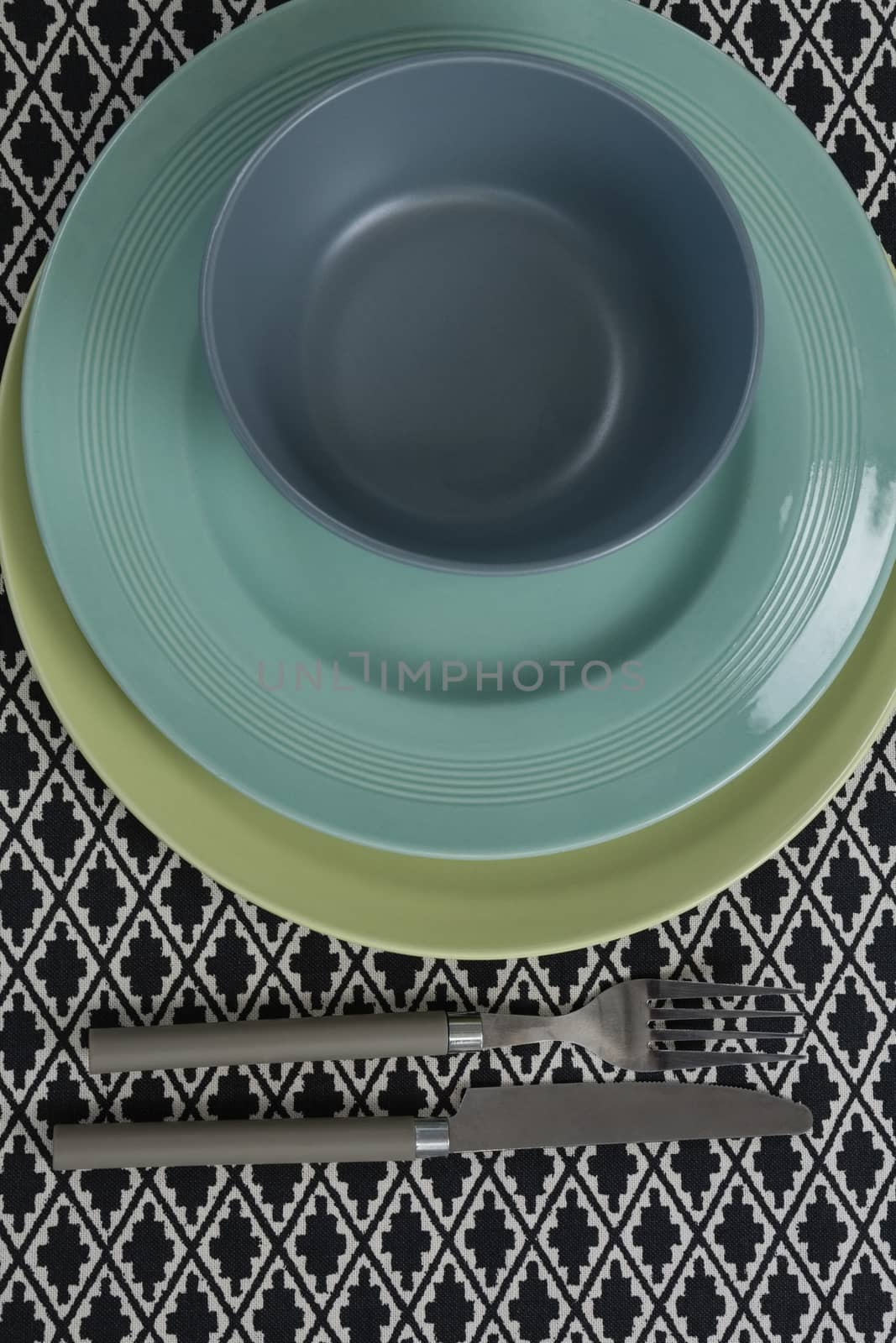 Close-up of fork and butter knife with bowl and plates on table cloth