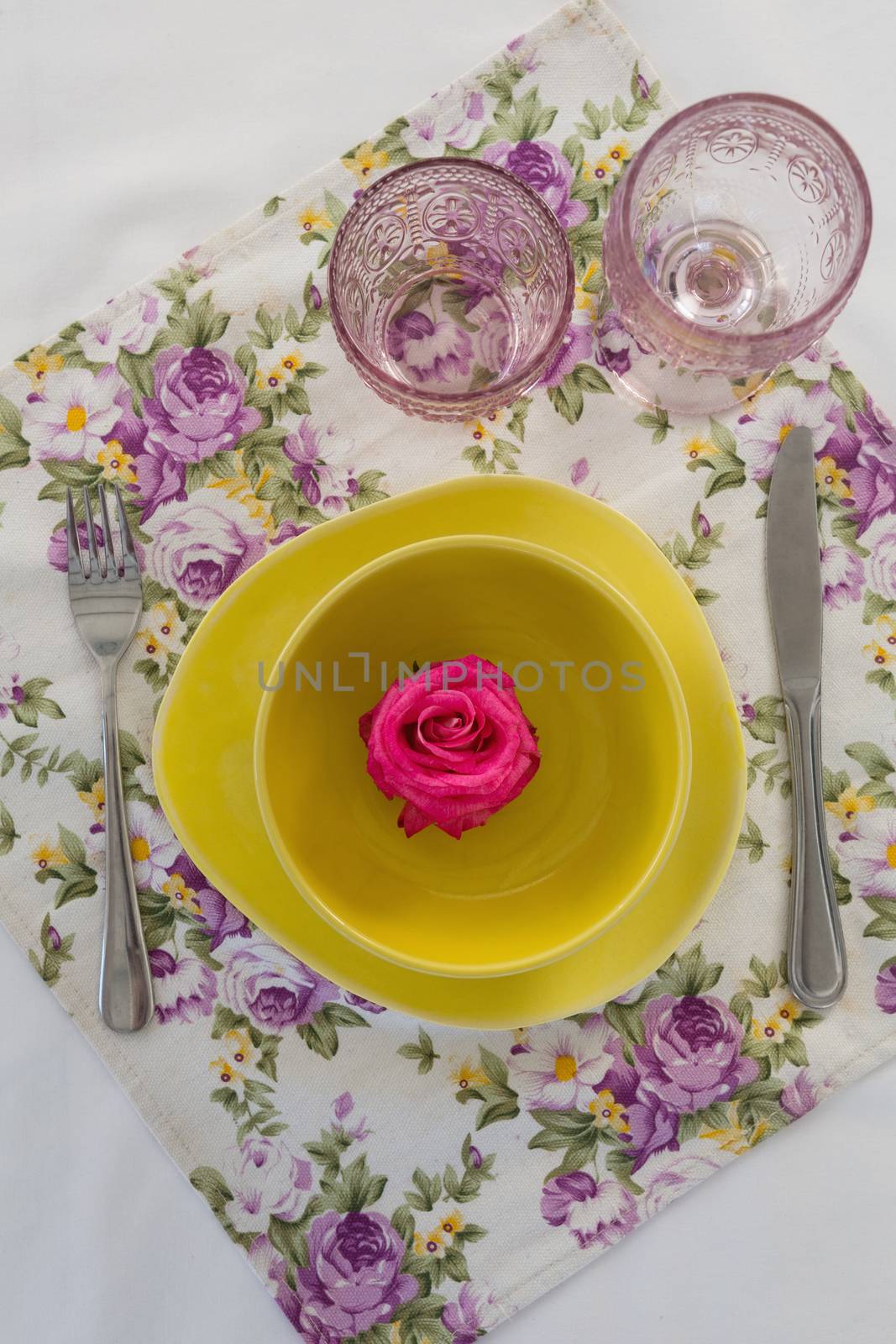 Overhead view of rose flower in a bowl with cutlery