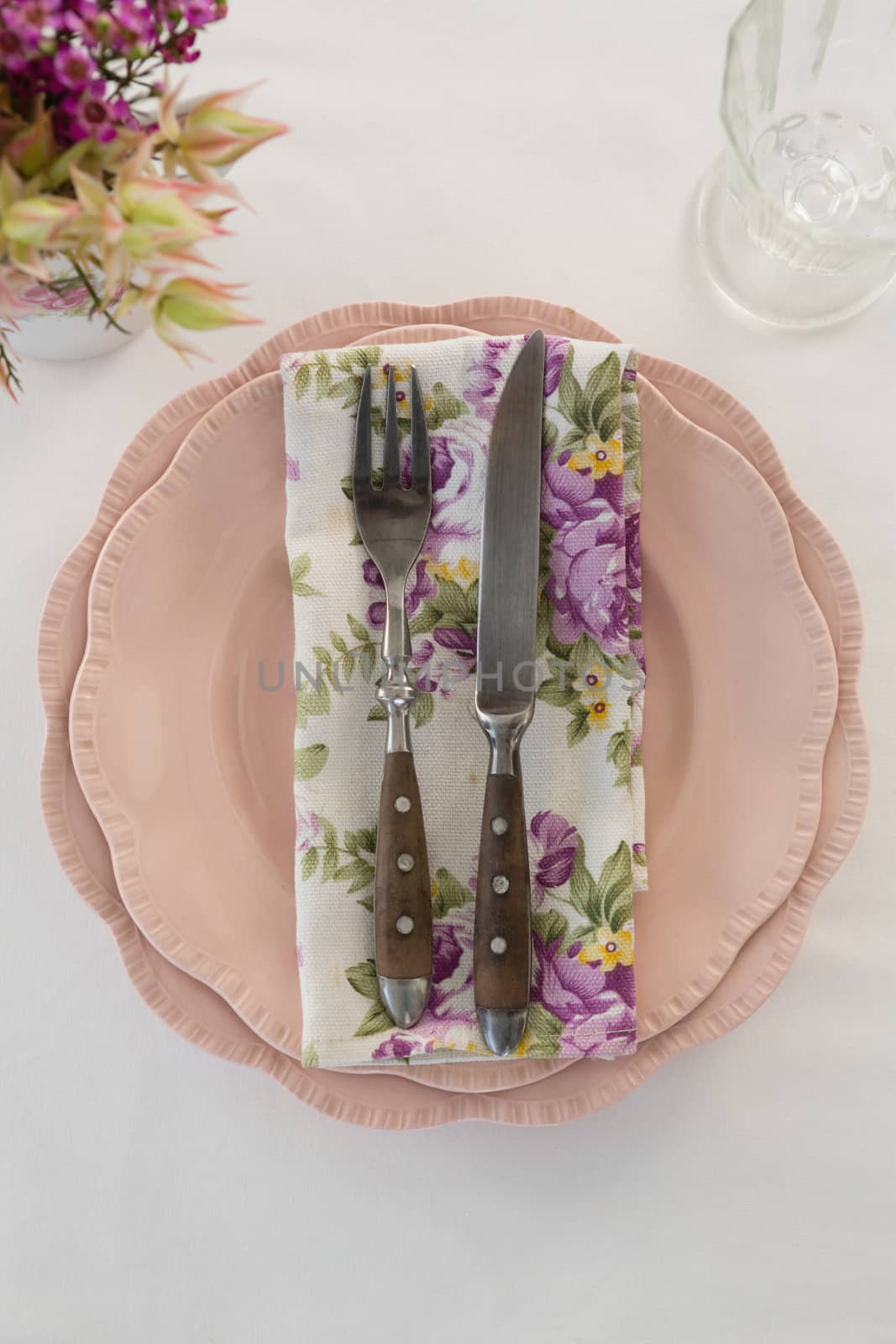 Fork, butter knife and napkin in a plate on white background