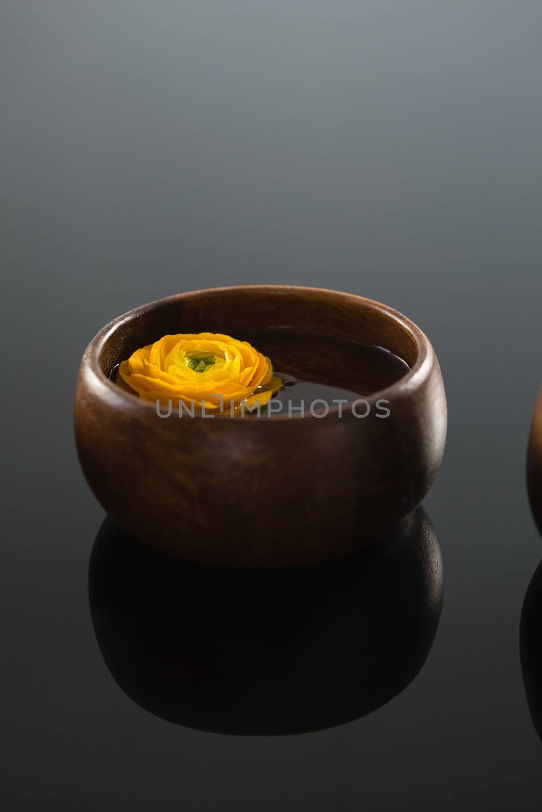 Close-up of yellow rose in glass bowl with water on black background