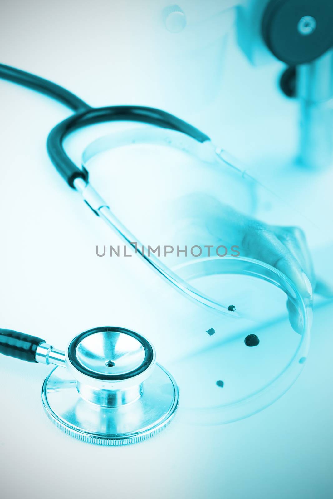 Metal black stethoscope against doctor holding microscope slide