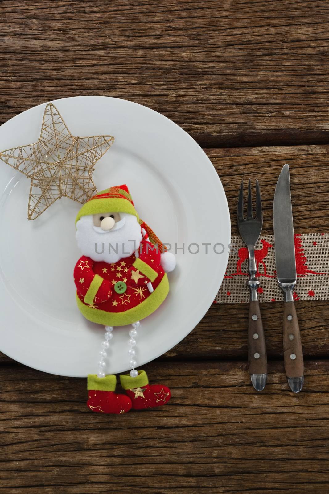 Santa claus with christmas ornament and cutlery on wooden table