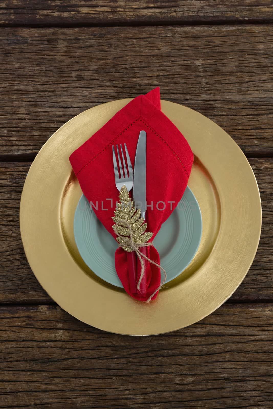 Overhead view of fork and butter knife with napkin and christmas ornament tied up with a rope