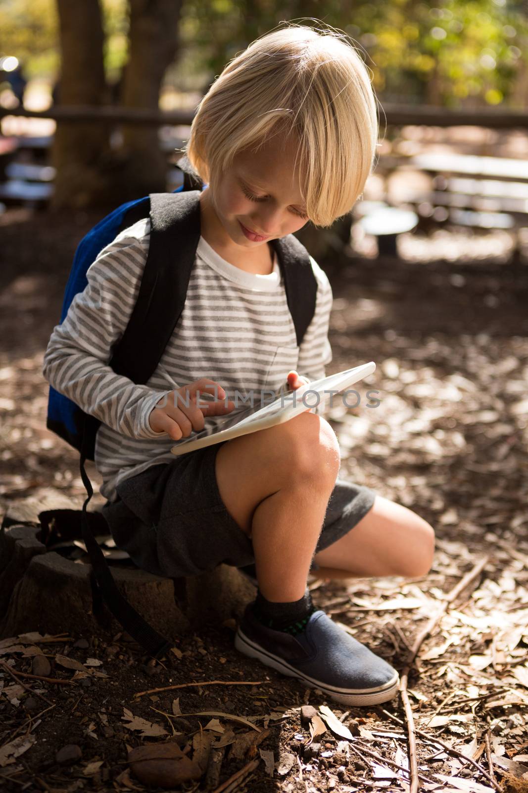 Little girl with a backpack using a tablet in the forest