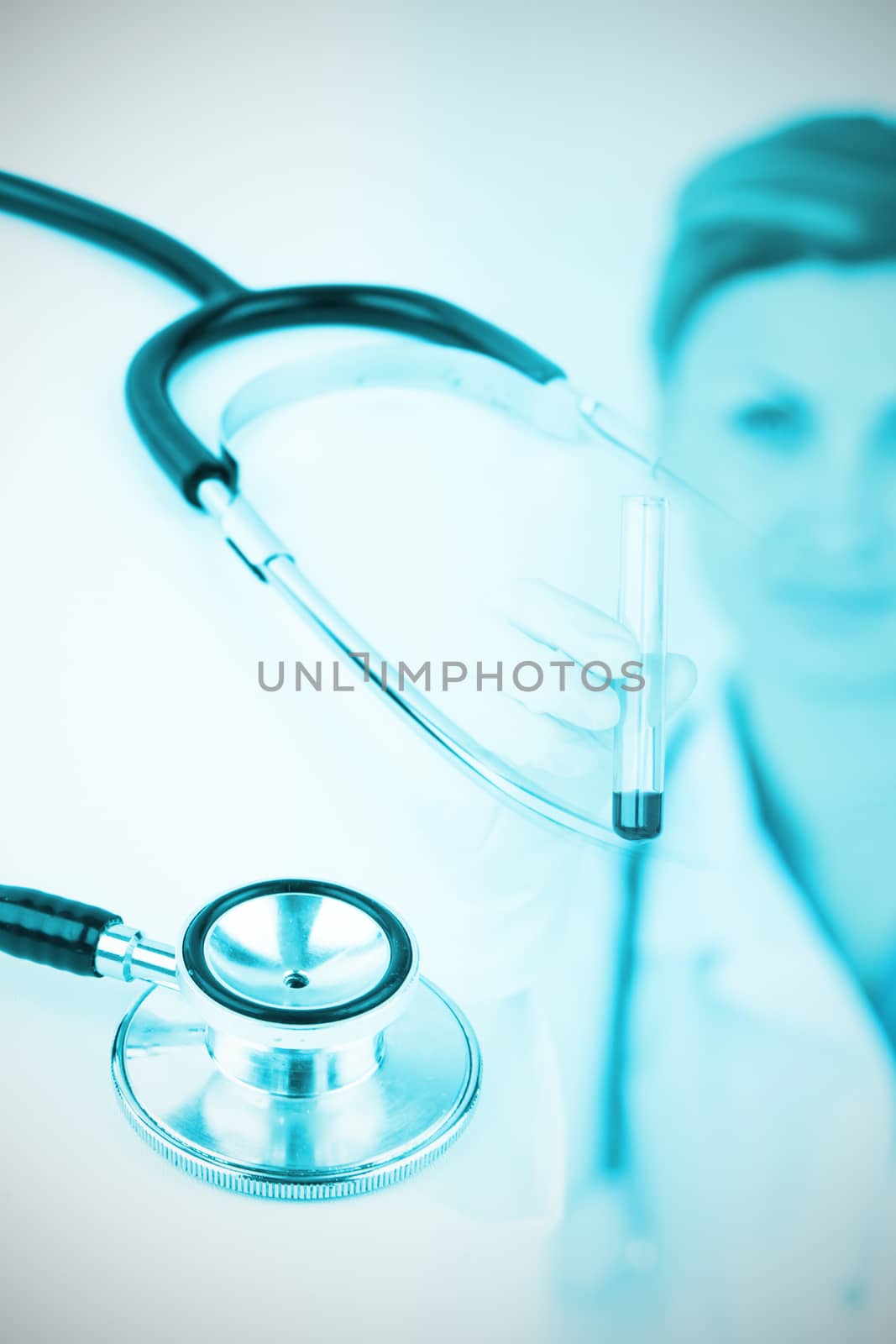 Metal black stethoscope against female scientist looking at the camera while holding a test tube