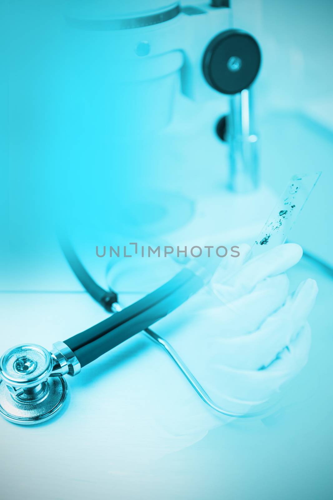 Stethoscope on desk against doctor using microscope in laboratory