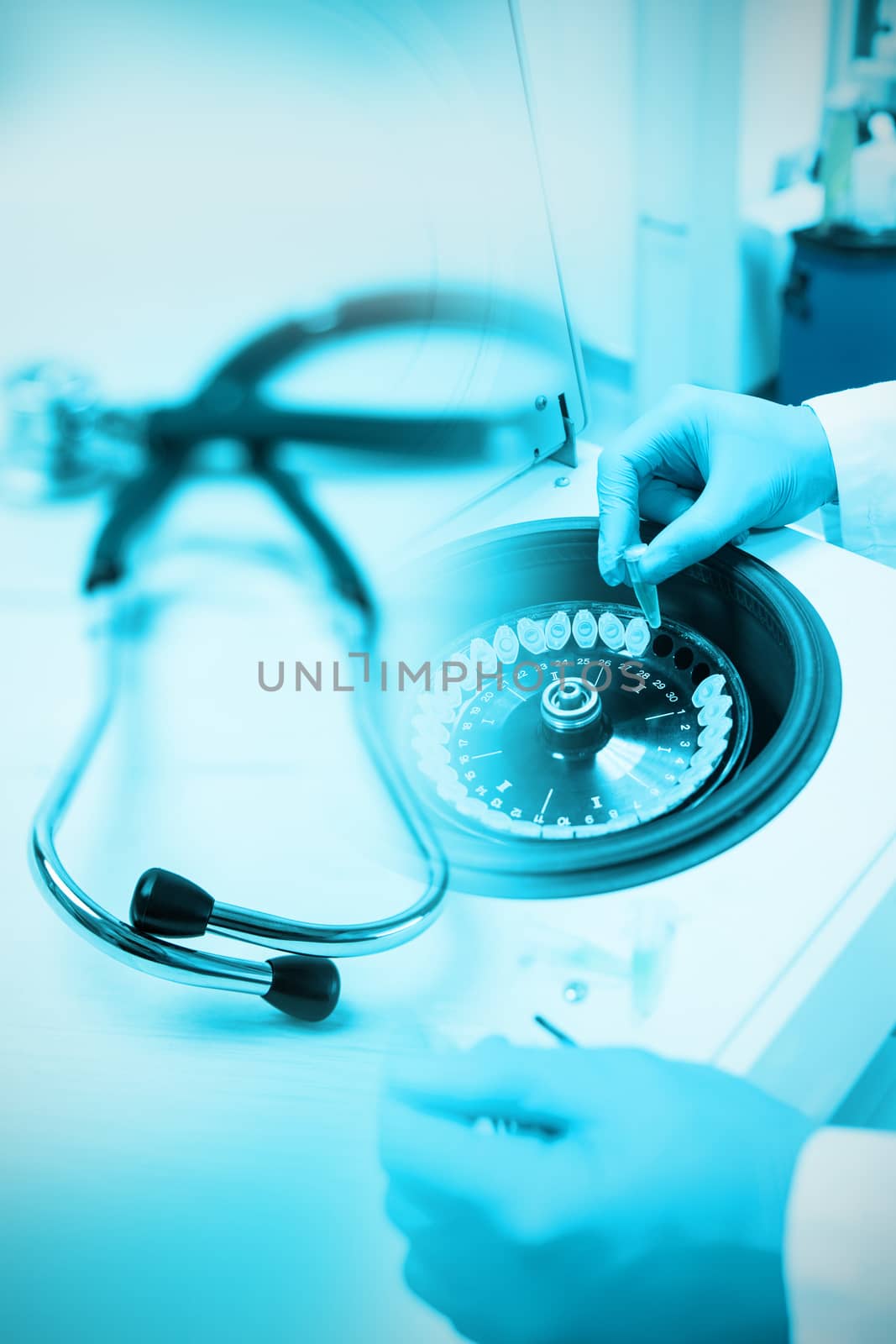 Stethoscope on desk against close up of a chemist using a centrifuge