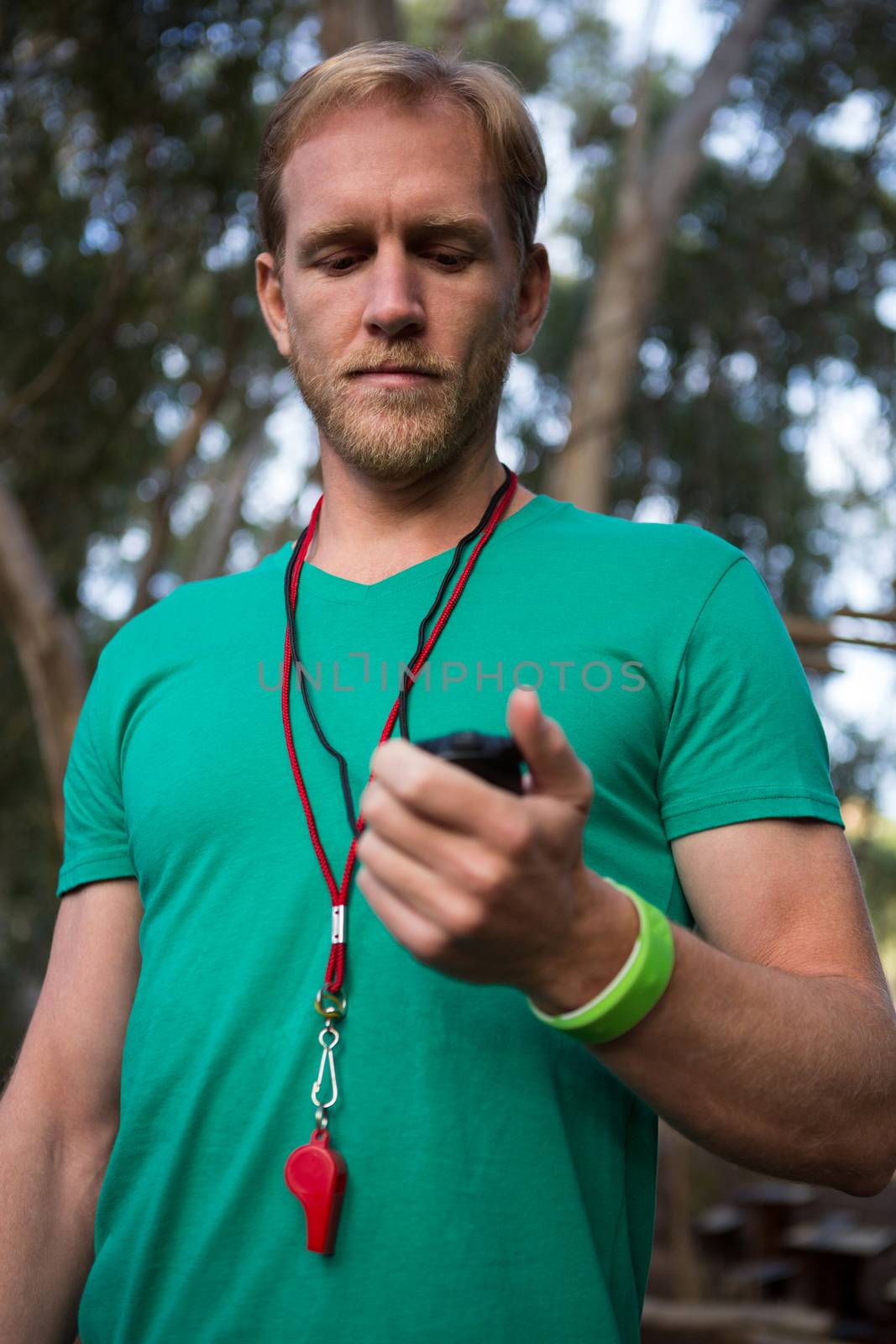 Close-up of trainer holding stop watch in his hand in the forest