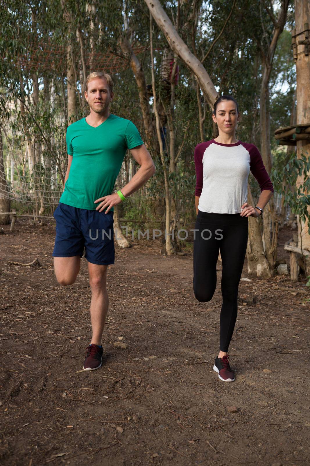 Woman exercising along with her trainer in the forest