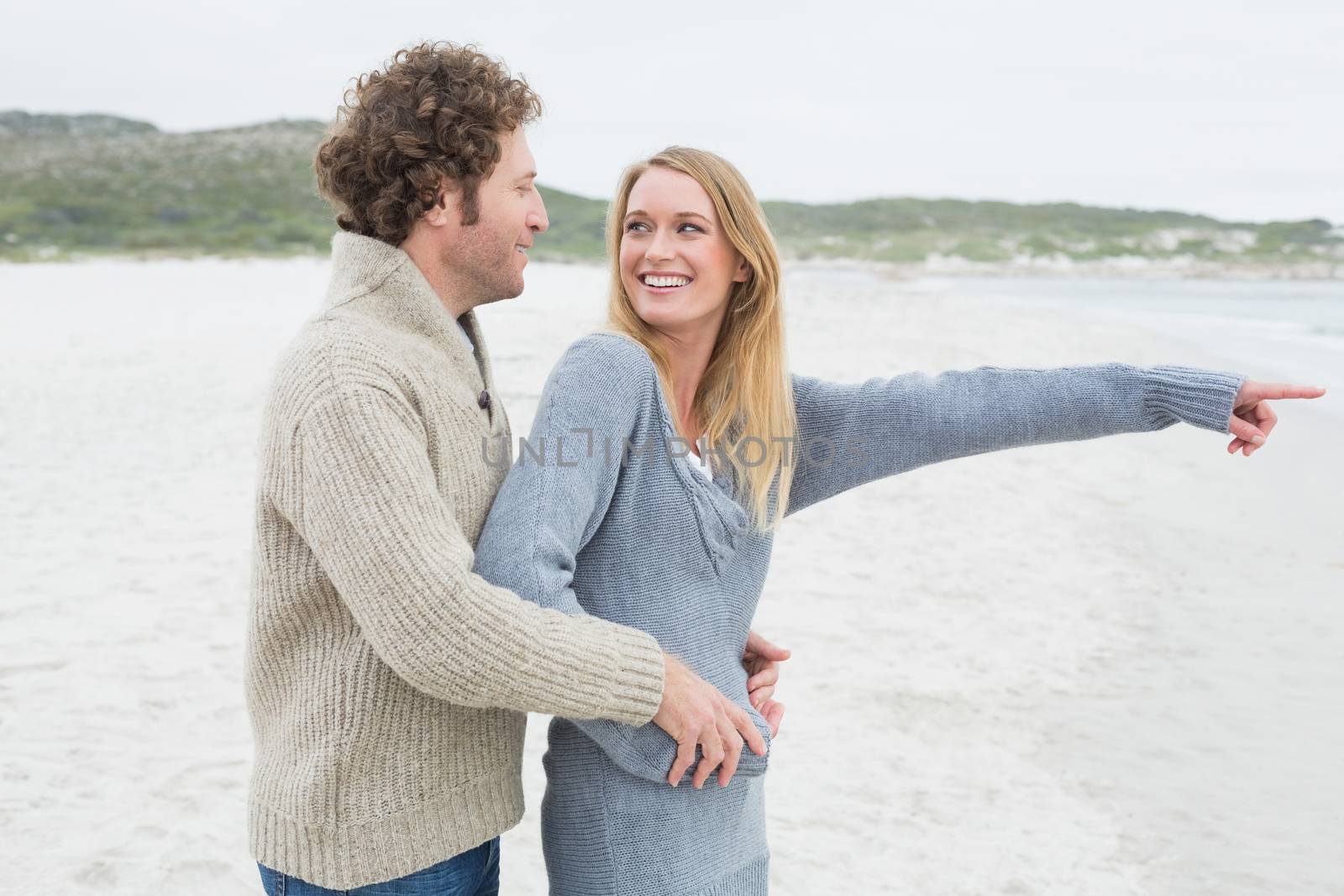 Side view of a relaxed romantic young couple standing together at the beach