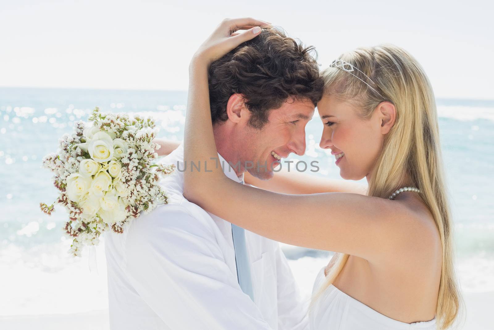 Romantic couple hugging on their wedding day at the beach