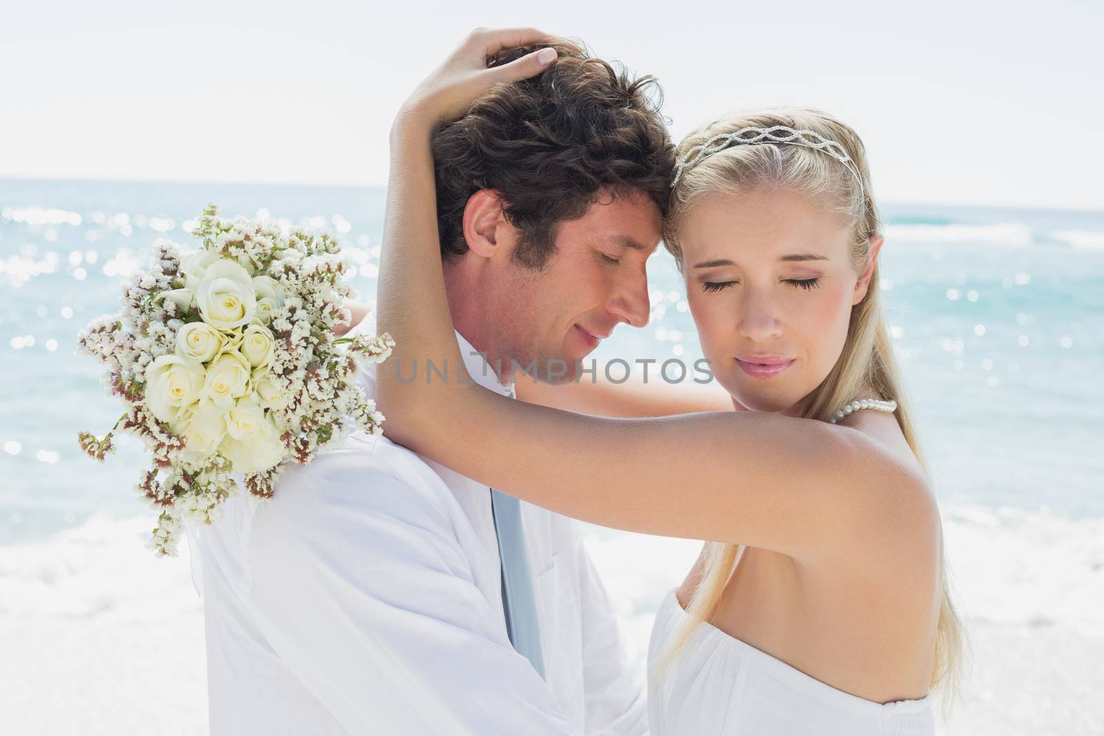 Romantic couple embracing on their wedding day at the beach