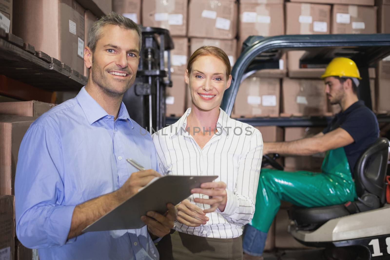 Warehouse team working together with clipboard in a large warehouse