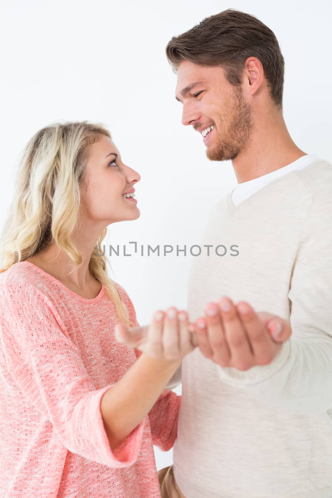 Attractive young couple holding out palms over white background