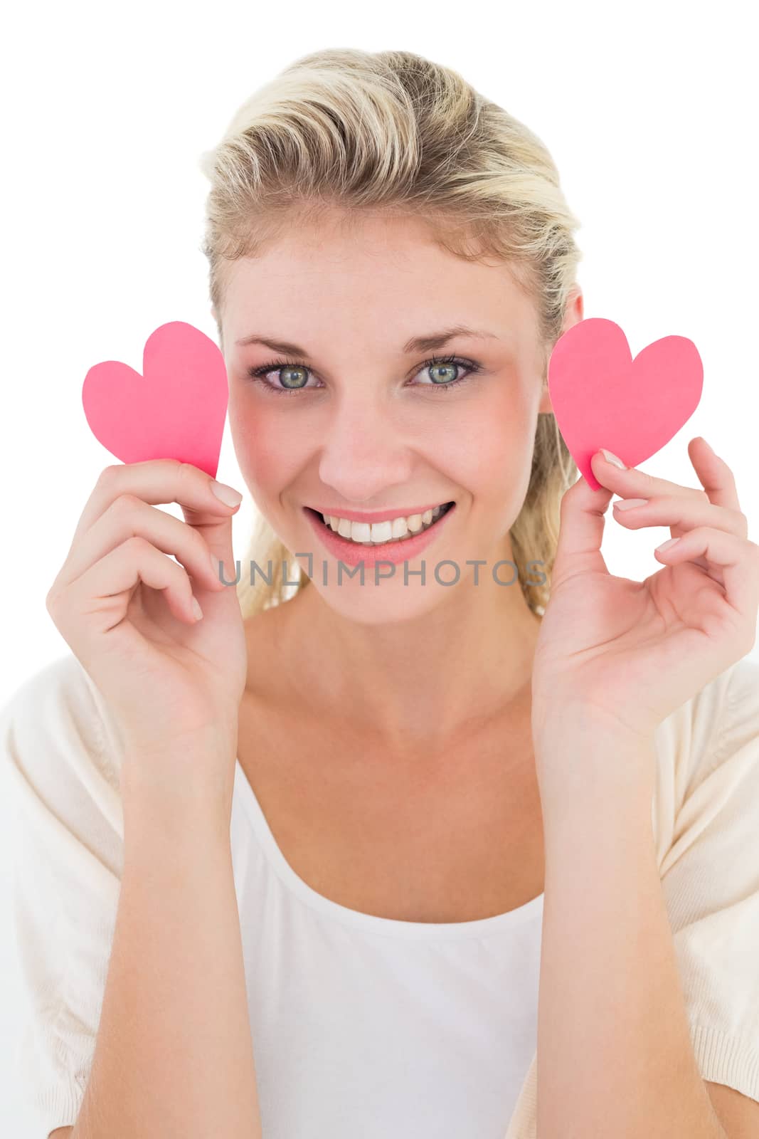 Portrait of smiling young woman holding pink hearts over white background