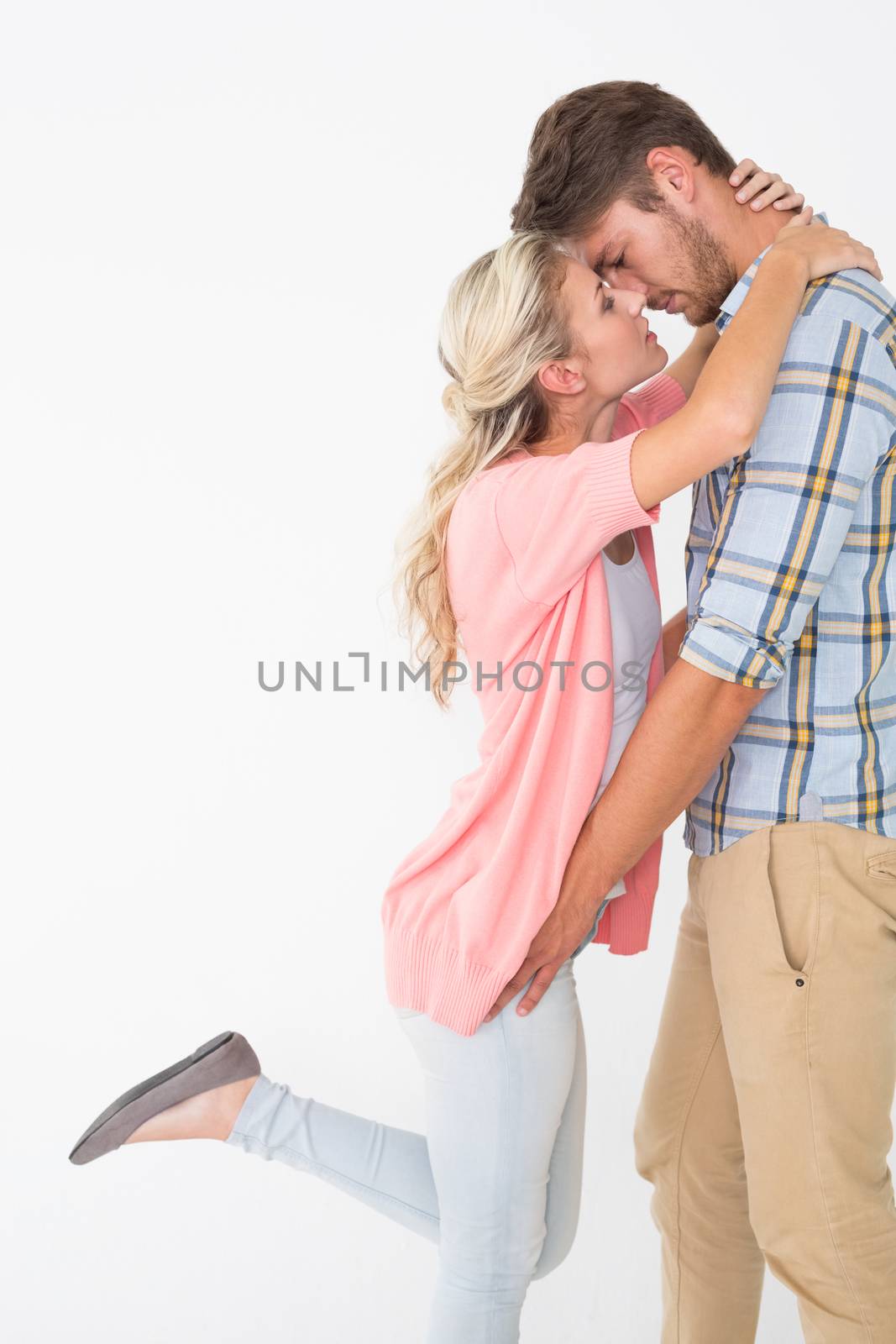 Side view of romantic young couple about to kiss over white background