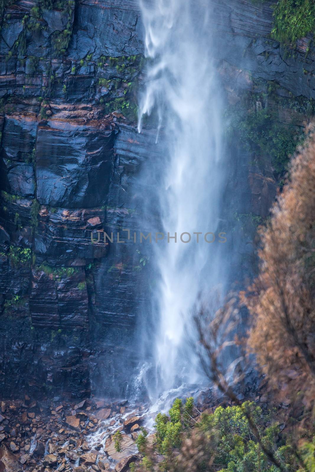 Waterfall tumbling down onto boulders at its base by lovleah